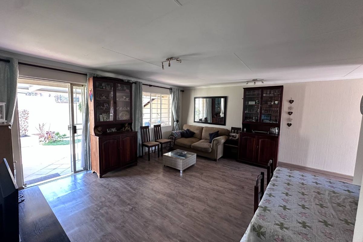 Spacious living area featuring laminate flooring, neutral walls, and a sliding glass door providing direct access to the outdoor patio area.