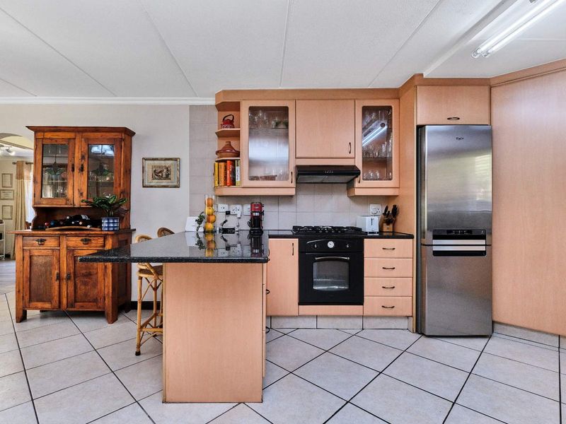 Functional kitchen featuring light wood cabinetry, granite countertops, built-in oven, gas hob, and tiled flooring, offering a practical layout for daily cooking.