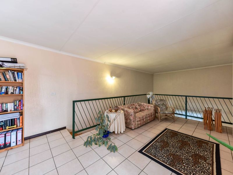 A spacious living area featuring tiled flooring and a metal balustrade overlooking the lower level, providing a functional and open layout.
