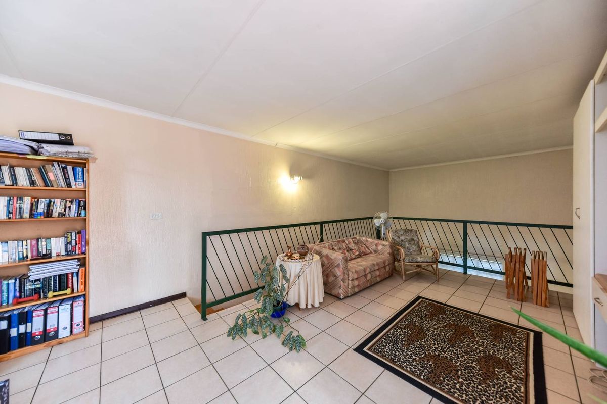 A spacious living area featuring tiled flooring and a metal balustrade overlooking the lower level, providing a functional and open layout.