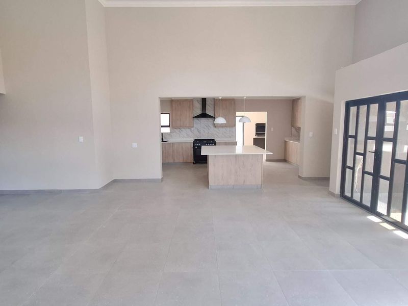 Spacious open-plan living area featuring a modern kitchen with a central island, sleek cabinetry, and large format floor tiles.