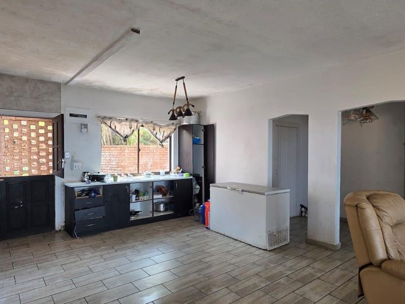 Open-plan kitchen and living area featuring tiled flooring, built-in cabinetry, and a gas stove, offering a functional layout with potential for modernization.