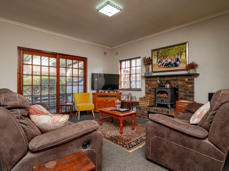 Cozy living room featuring a traditional brick fireplace with a wood-burning stove, timber-framed windows, and sliding glass doors leading to the exterior.
