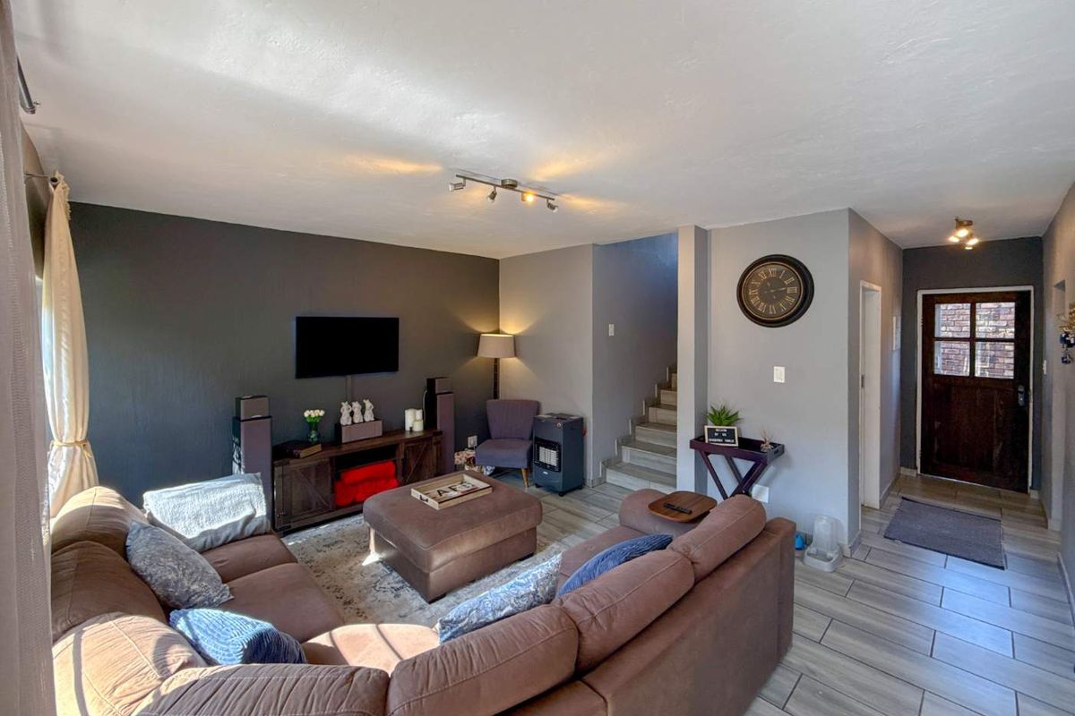 Spacious living room featuring tiled flooring, a staircase, and a timber front door, creating a welcoming and functional open-plan entrance area.