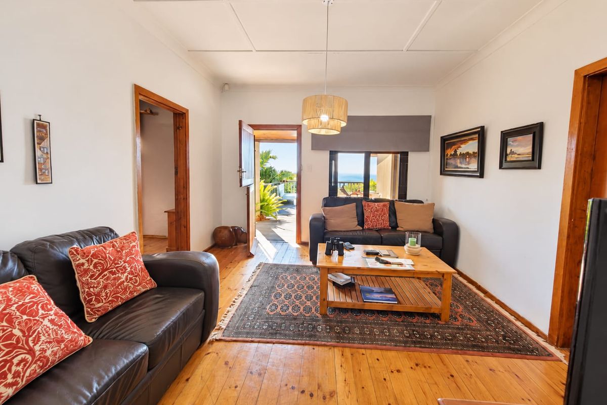 A bright living room featuring polished timber flooring, a panelled ceiling, and direct access to an outdoor patio area.