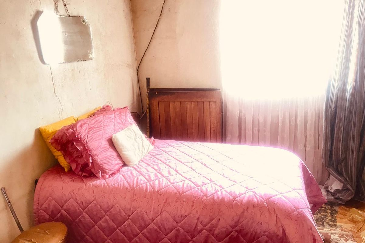 A bedroom space requiring significant renovation, featuring visible wall cracks and dated finishes, offering potential for a complete modern transformation.