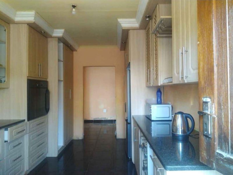 A functional kitchen featuring built-in cabinetry, granite countertops, and a built-in oven, with tiled flooring throughout.