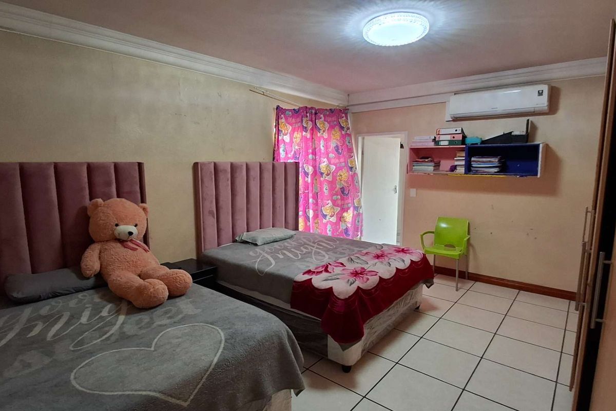 A bedroom featuring tiled flooring, a wall-mounted air conditioning unit, and built-in shelving, requiring cosmetic updates to the wall finishes.
