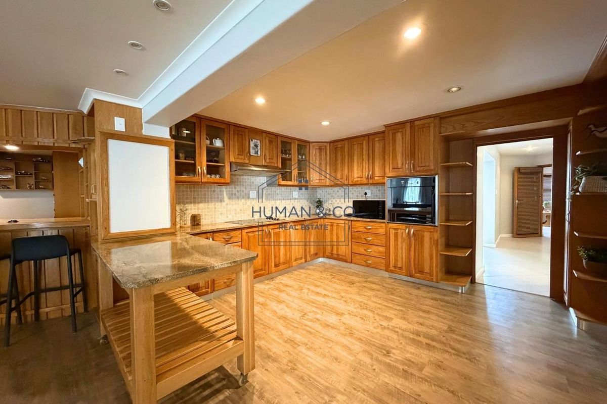 A spacious kitchen featuring extensive wooden cabinetry, granite countertops, built-in oven, and recessed lighting, offering a functional layout with ample storage space.