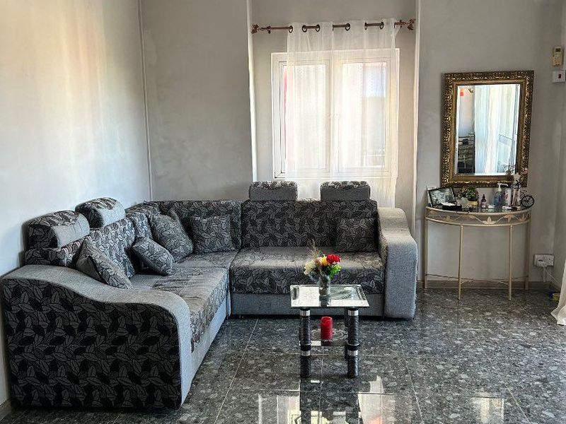 A living room featuring polished terrazzo flooring, a wall-mounted air conditioning unit, and neutral wall finishes.