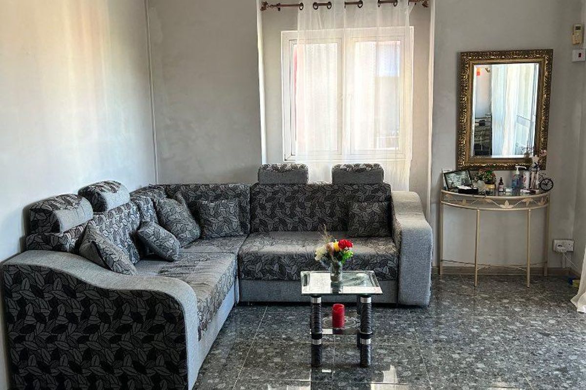 A living room featuring polished terrazzo flooring, a wall-mounted air conditioning unit, and neutral wall finishes.