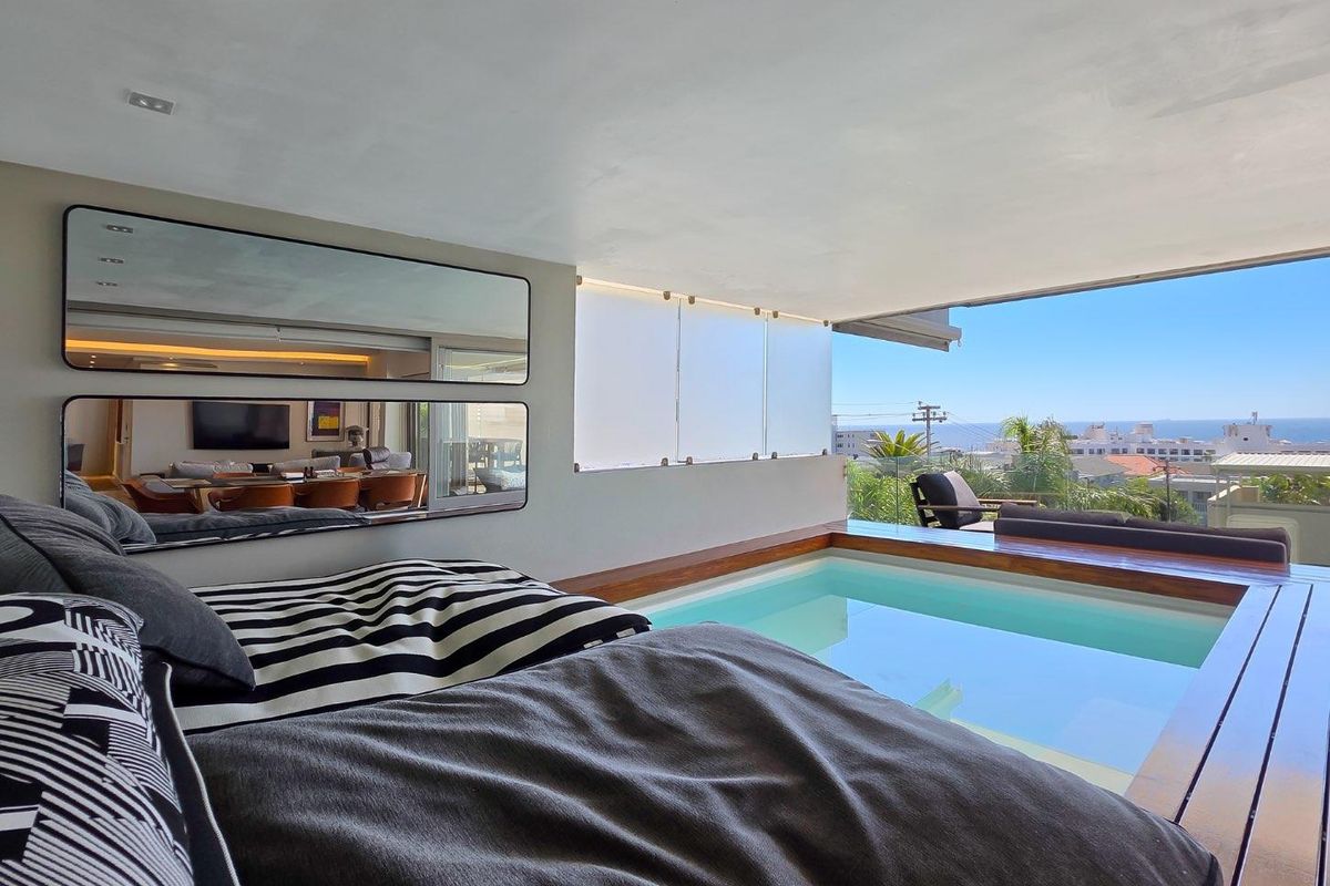 A unique bedroom suite featuring an integrated indoor plunge pool with timber decking and expansive views through a glass balustrade.