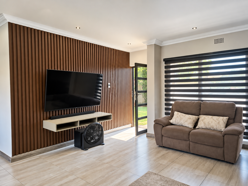Modern living room featuring a stylish slatted timber accent wall, tiled flooring, recessed lighting, and large windows with contemporary roller blinds.