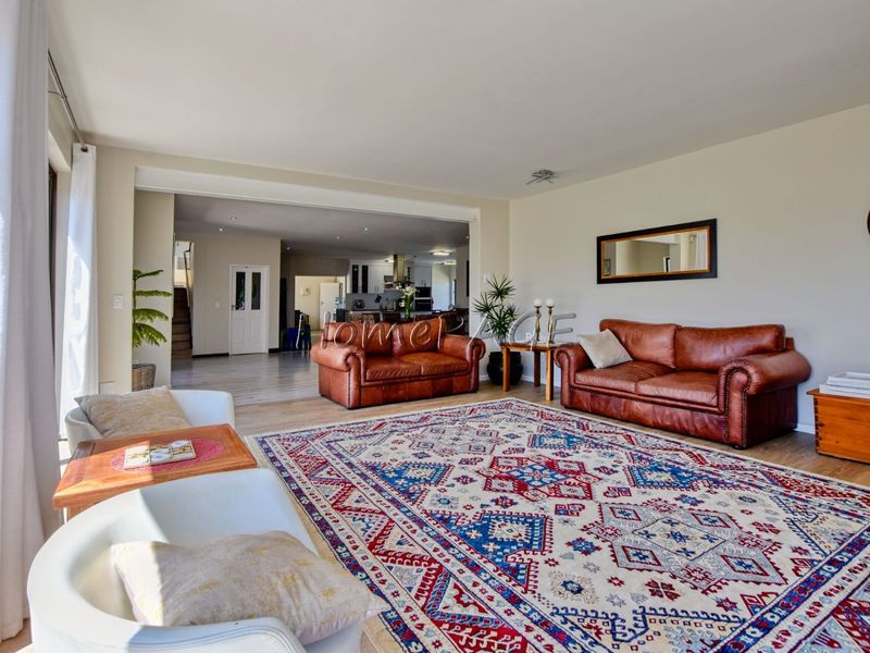 Spacious open-plan living area featuring laminate flooring, recessed lighting, and seamless flow into the kitchen and dining space.