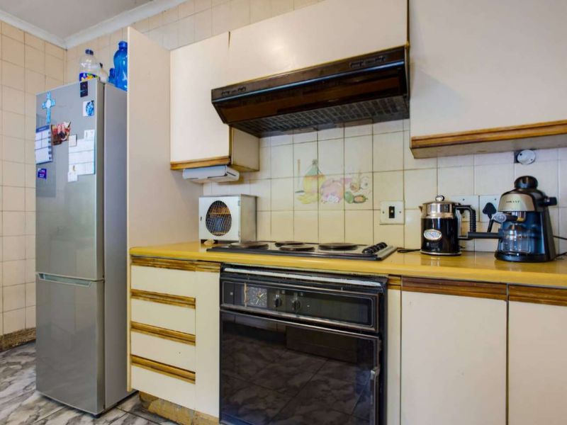 A dated kitchen featuring original cabinetry, laminate countertops, and built-in cooking appliances, offering significant potential for a modern renovation.