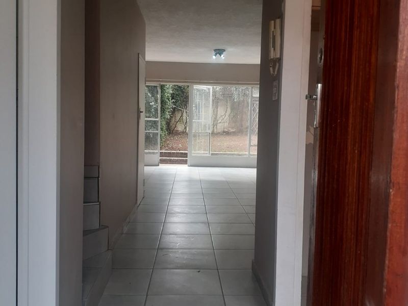 A bright, tiled entrance hallway leading through to an open living area with large sliding glass doors providing access to the rear garden.