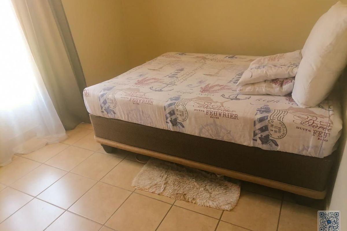 A bedroom featuring tiled flooring and a window with curtains.