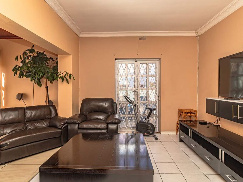 A living room featuring ceramic floor tiles, crown molding, and a security gate leading to the exterior.