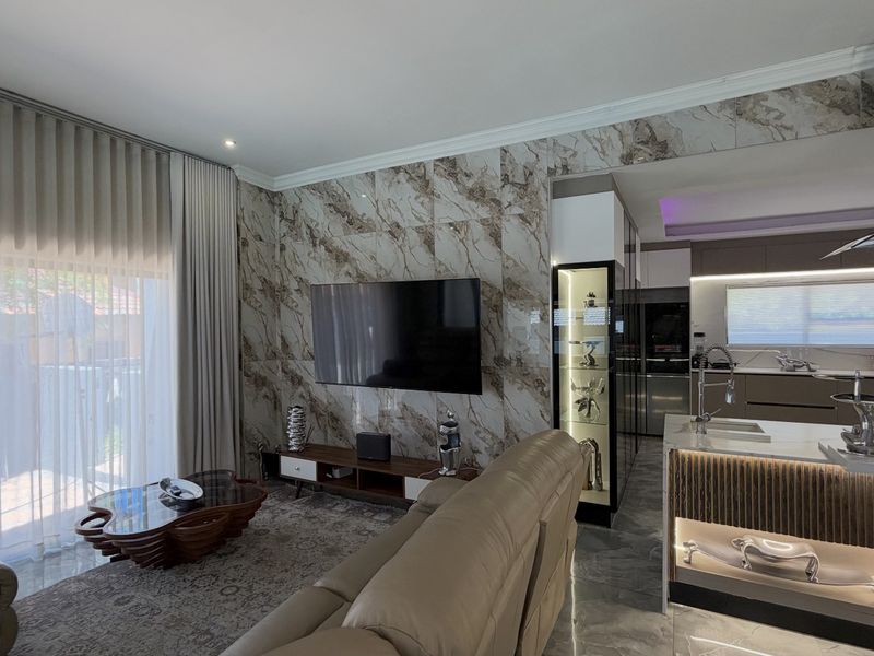 Modern open-plan living area featuring a striking marble-tiled feature wall, sleek kitchen island with integrated lighting, and high-end finishes throughout.