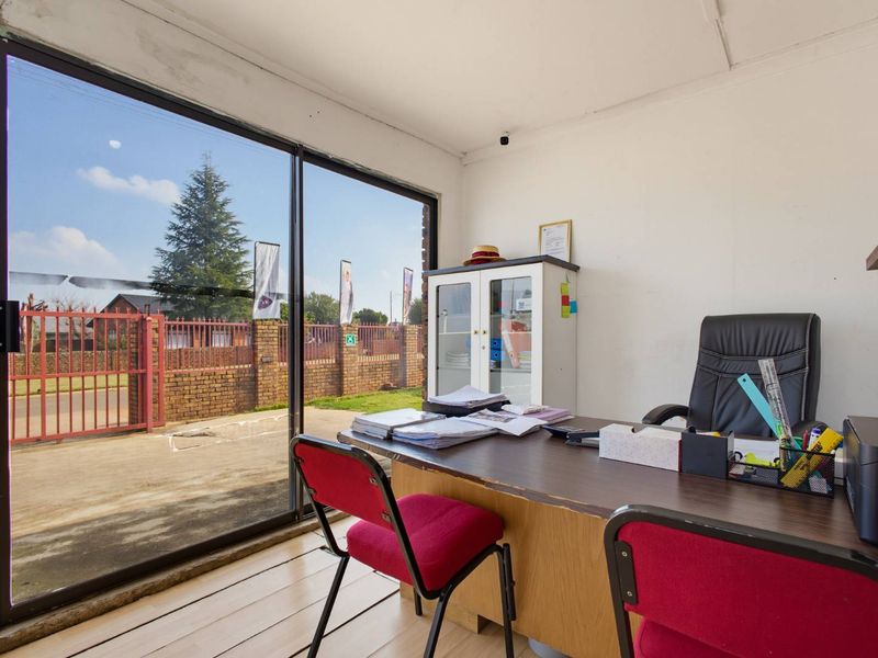 A functional office space featuring laminate flooring and a large sliding glass door providing natural light and exterior views.