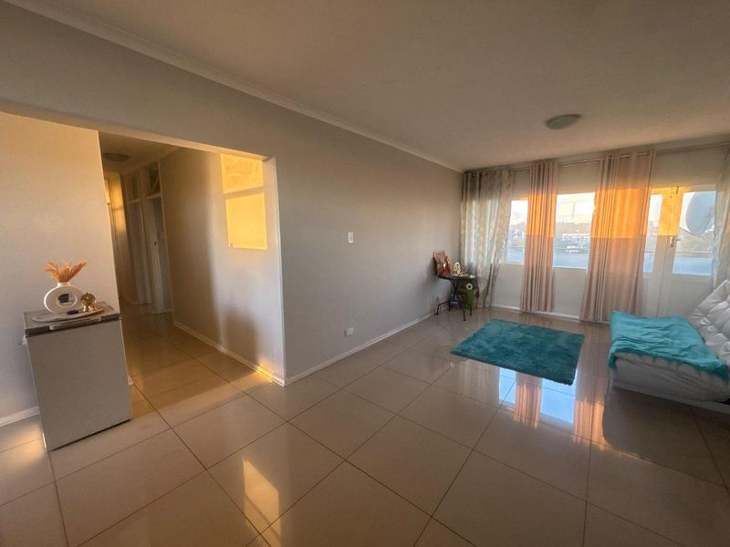 A bright living room featuring neutral tiled flooring and a sliding glass door that provides access to an outdoor area.