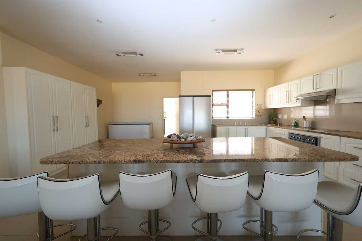 Spacious kitchen featuring a large granite-topped island, ample white cabinetry, integrated oven, and extractor fan, providing a functional and bright cooking space.