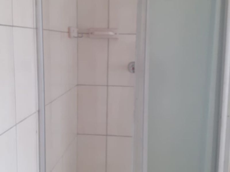 A functional shower stall featuring white wall tiles and a glass enclosure.