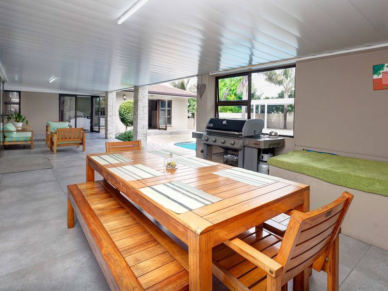 Spacious covered patio featuring tiled flooring, built-in bench seating, and direct access to the garden and pool area.