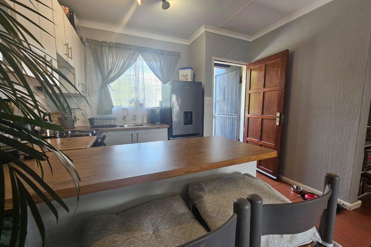 A functional kitchen featuring built-in cabinetry, a wooden breakfast bar, and direct access to an exterior doorway.