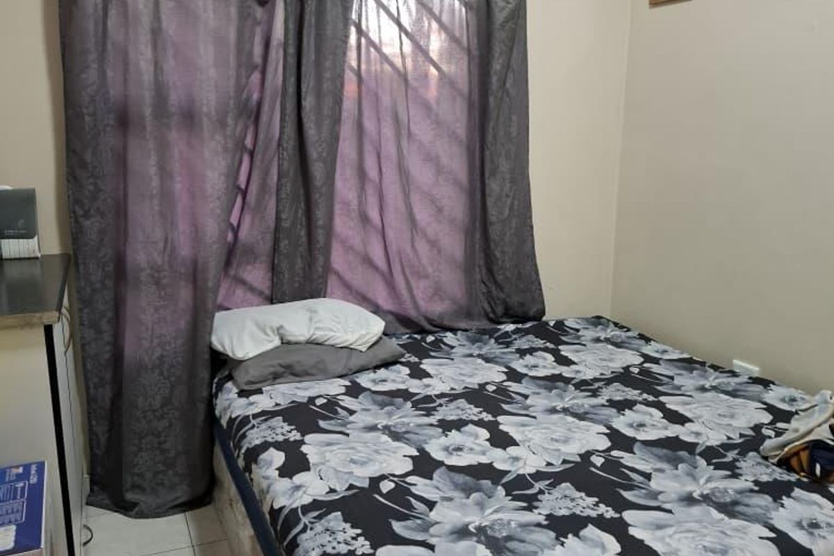 A functional bedroom featuring tiled flooring and window security bars, providing a basic and practical living space.