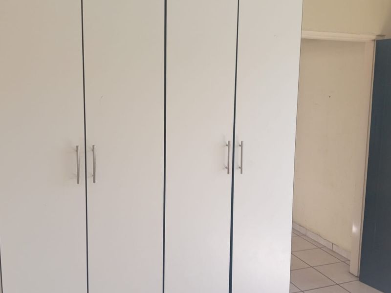 A bedroom featuring built-in cupboards and tiled flooring, presenting a clean and functional space ready for personalization.
