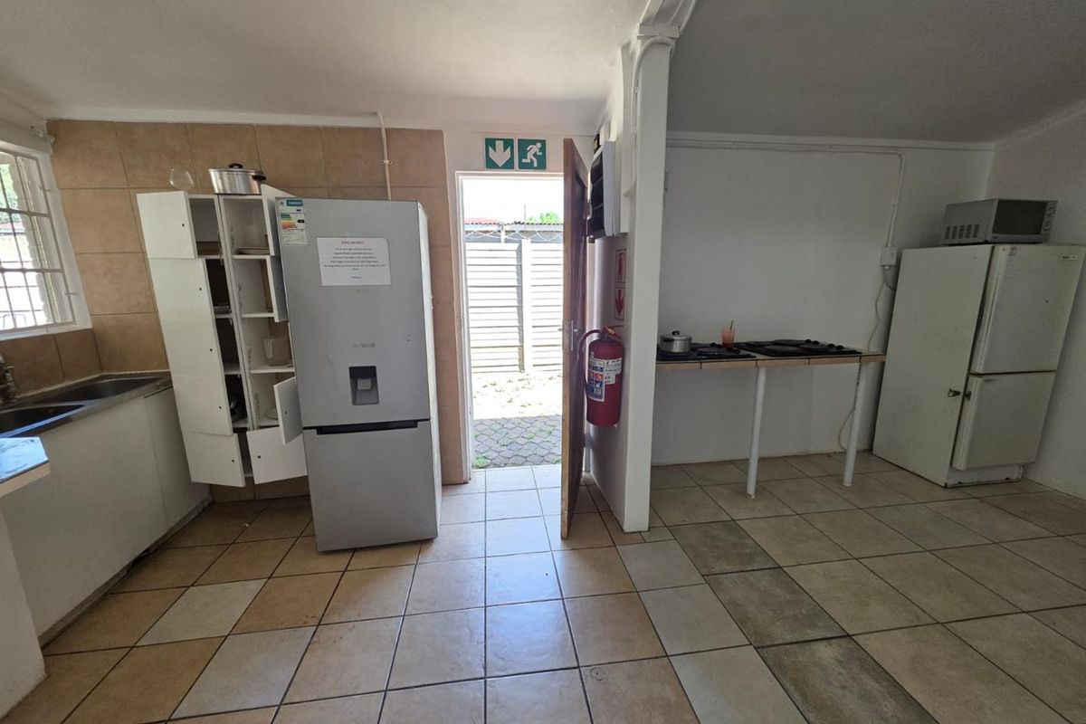 A functional kitchen area featuring tiled flooring, basic cabinetry, and direct access to an outdoor space, suitable for renovation or modernization.