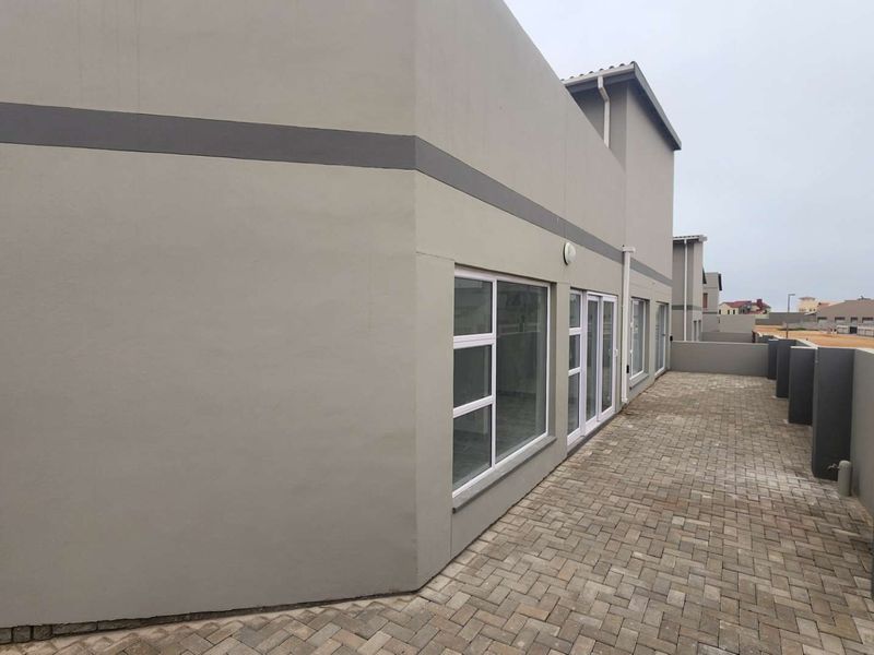A view of the rear exterior of the townhouse featuring a paved patio area and modern sliding glass doors.
