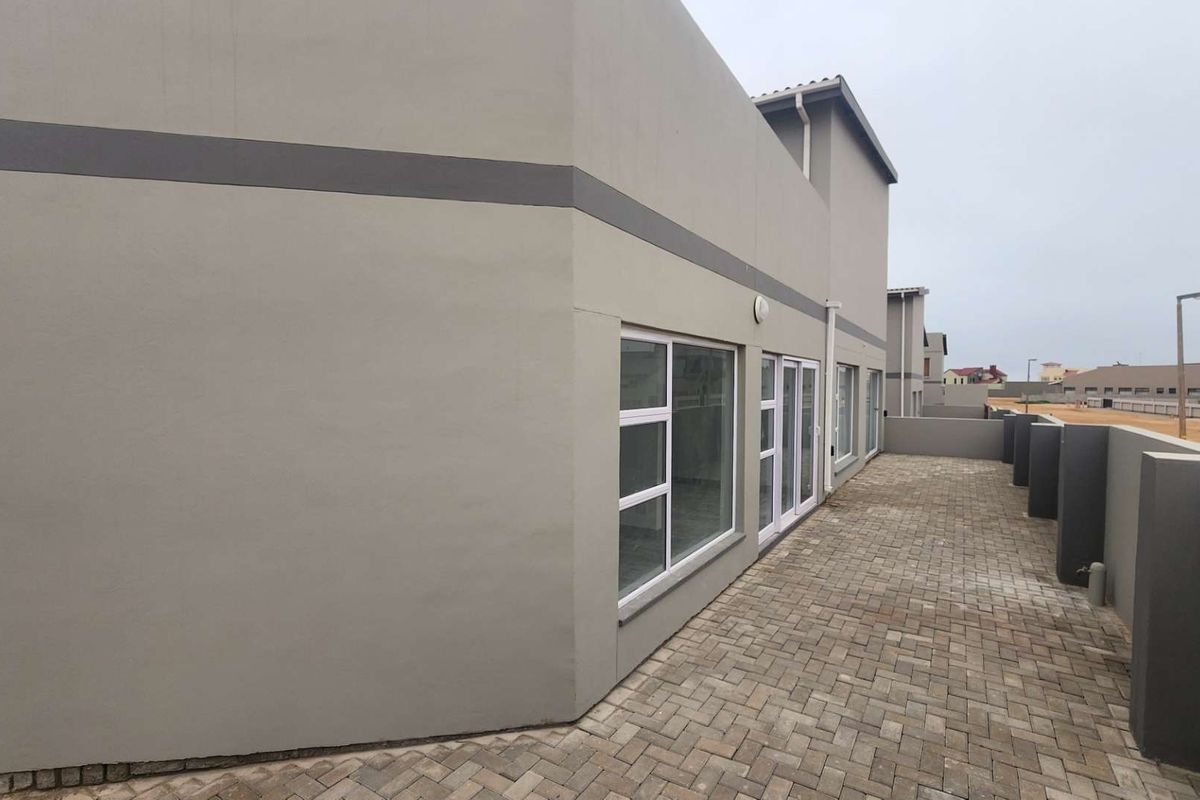 A view of the rear exterior of the townhouse featuring a paved patio area and modern sliding glass doors.