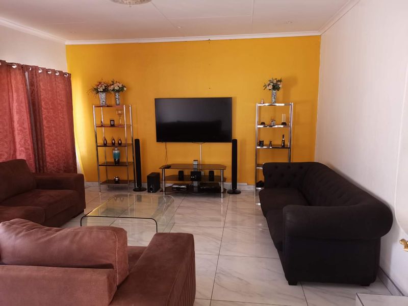 A living room featuring large format floor tiles and a bold yellow accent wall, providing a bright and functional space for relaxation.