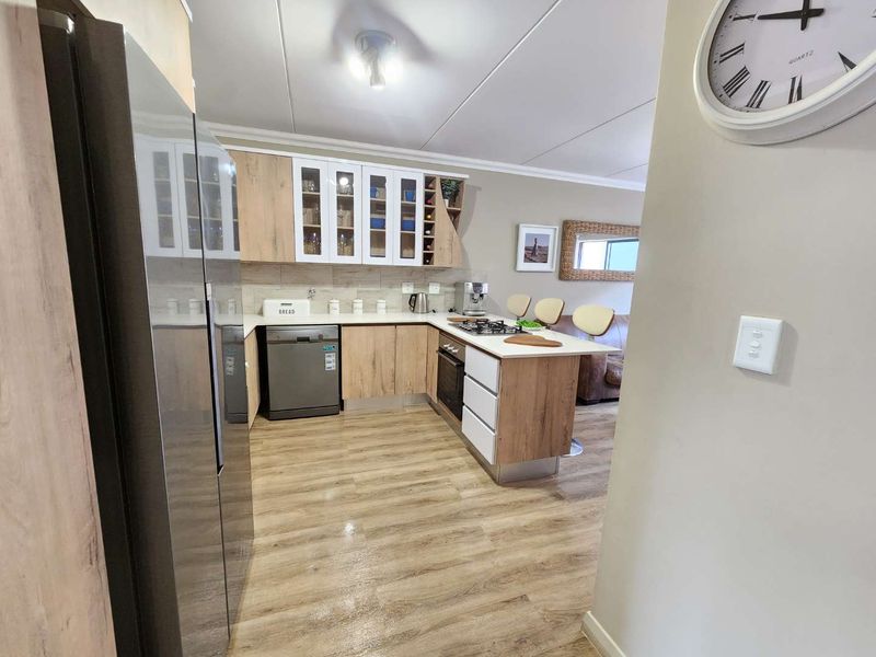 Modern kitchen featuring light wood-tone cabinetry, integrated appliances, gas cooktop, and durable laminate flooring, offering a functional and contemporary cooking space.