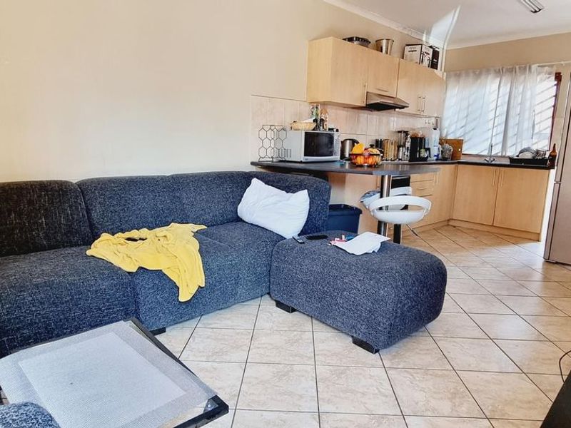 Open plan living area featuring tiled flooring and a functional kitchen with built-in cabinetry and an extractor fan.