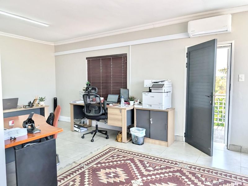 A functional office space featuring tiled flooring, an air conditioning unit, and direct access to an outdoor area through a modern door.