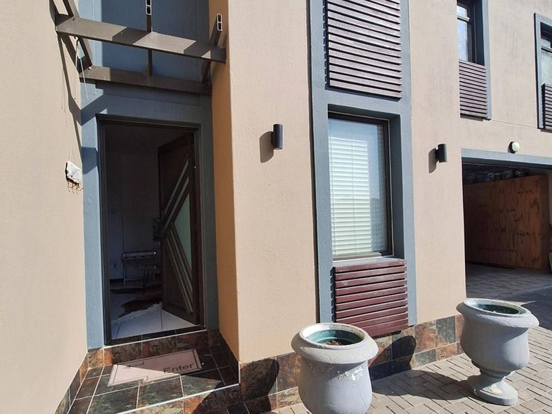 Modern front entrance featuring paved driveway, tiled steps, and architectural timber slat window detailing on a contemporary facade.
