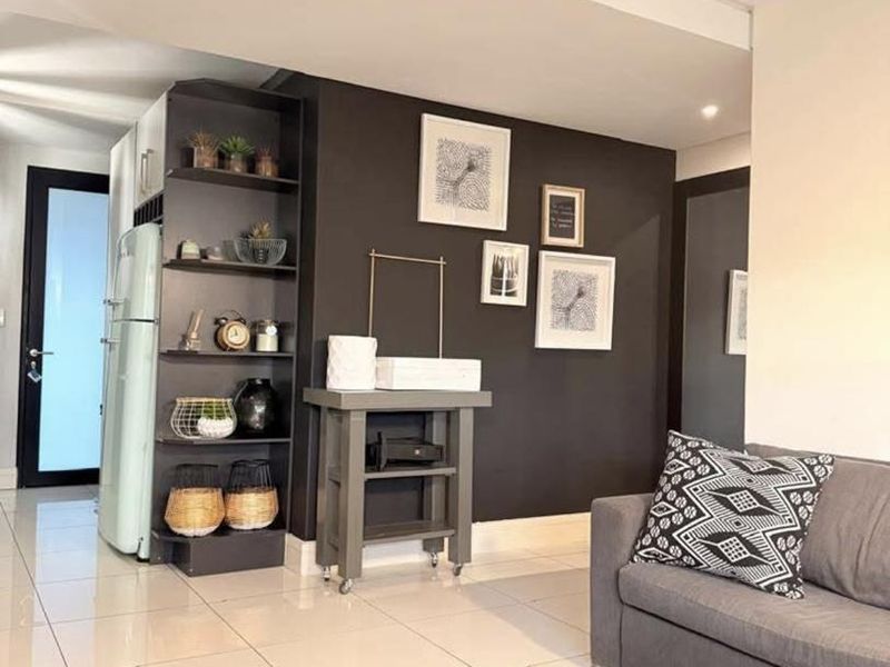 Open plan living area featuring modern tiled flooring, a dark accent wall, and integrated built-in shelving.