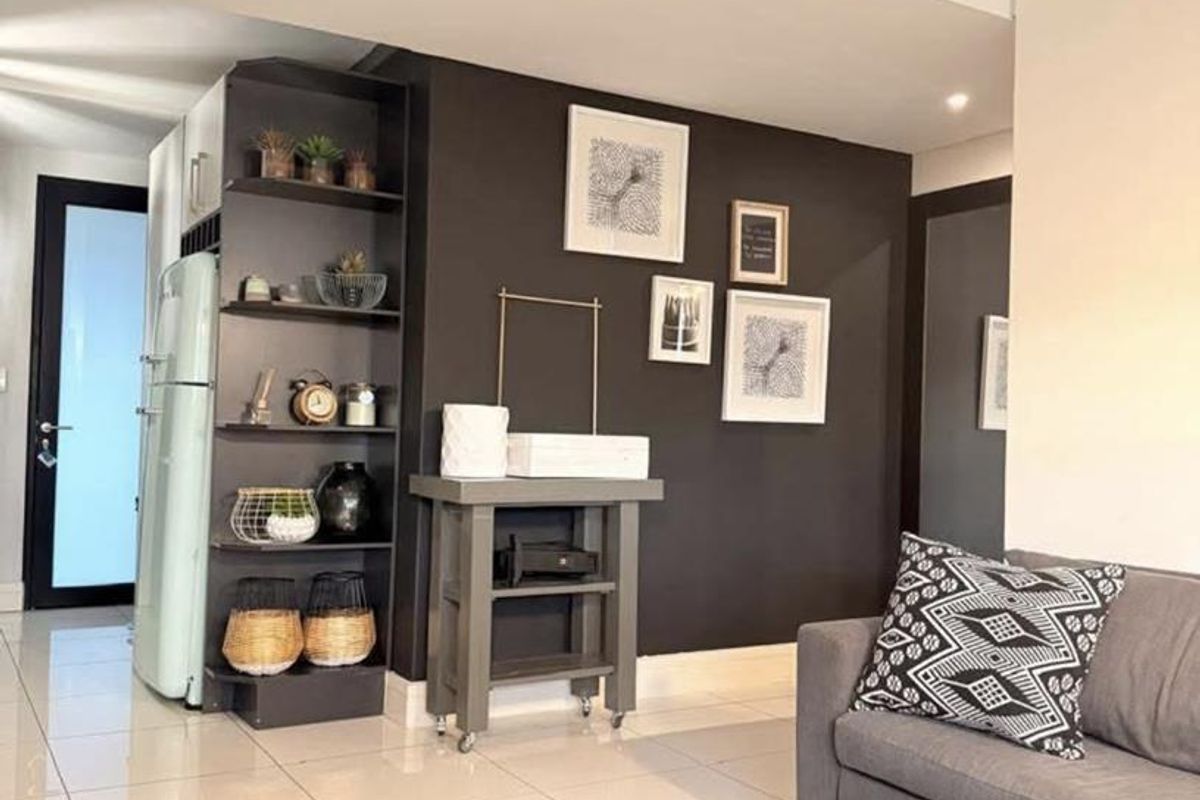 Open plan living area featuring modern tiled flooring, a dark accent wall, and integrated built-in shelving.