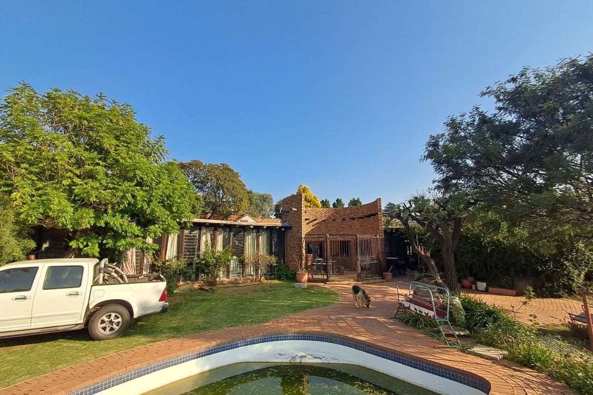 Rear exterior view of the house featuring a brick facade, a patio area, and a swimming pool requiring maintenance.