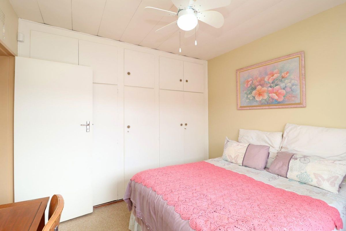 A bedroom featuring built-in cupboards, a ceiling fan, and carpeted flooring.