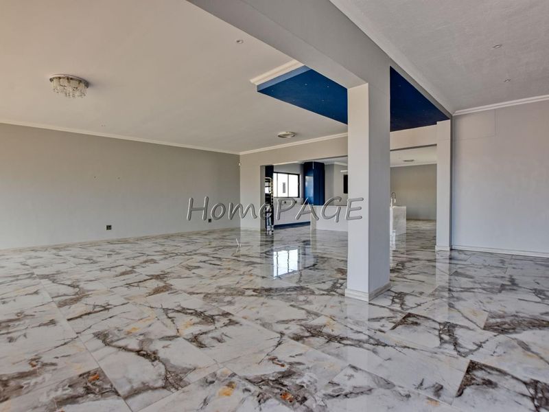 Spacious open-plan living area featuring polished marble-look floor tiles, a modern dropped ceiling detail, and neutral wall finishes.
