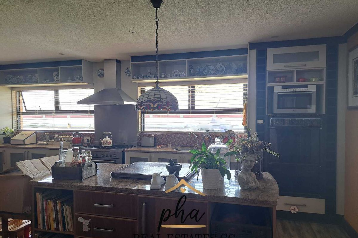 A functional kitchen featuring a central island, built-in oven, microwave, stainless steel extractor fan, and ample cabinetry with tiled splashbacks.