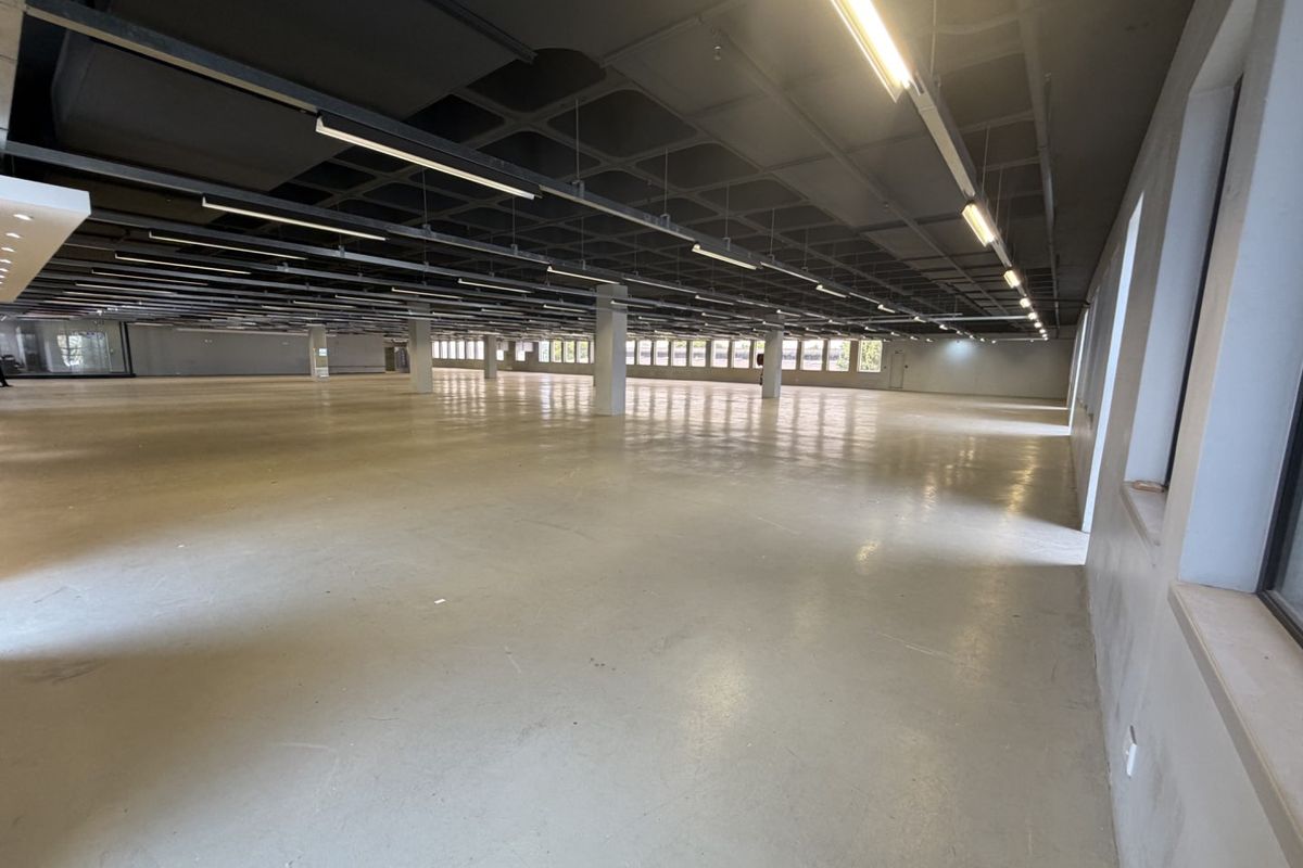 Expansive open-plan industrial floor space featuring polished concrete floors, exposed waffle ceiling, and abundant natural light from large windows.
