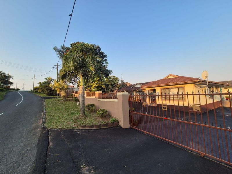 Front view of a residential property featuring a paved driveway, secure perimeter wall, and gated entrance.