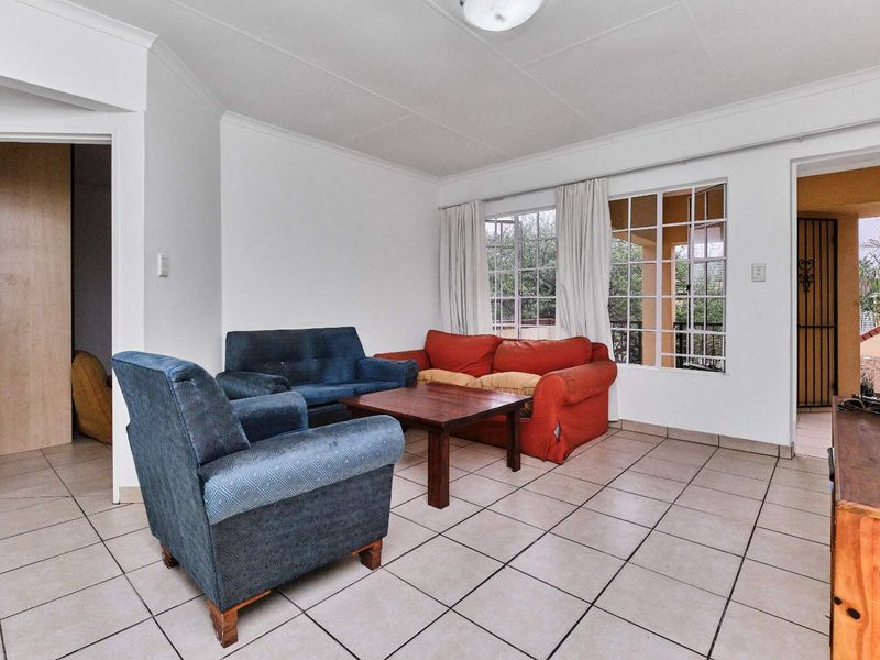 A living room featuring ceramic floor tiles, coved cornicing, and access to an outdoor area through a security gate.