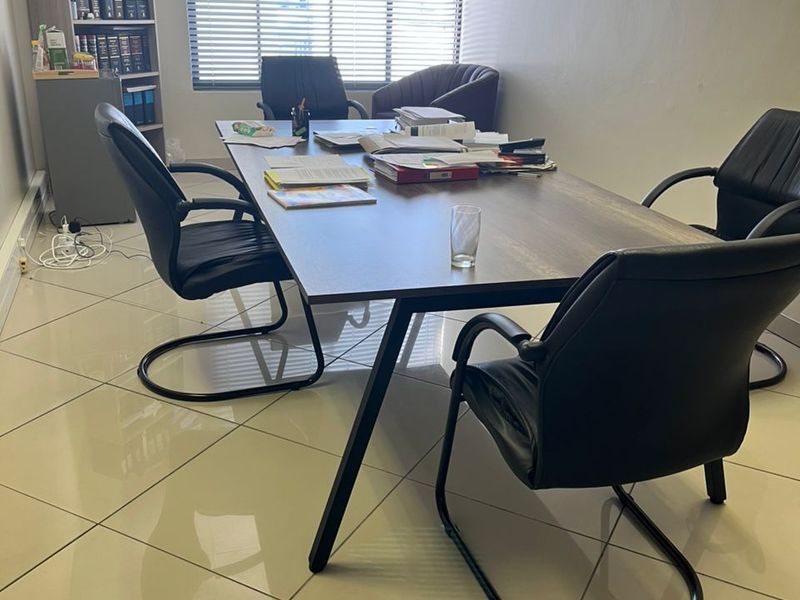 A functional office space featuring polished tiled flooring and large windows with venetian blinds, providing a professional environment for meetings or daily work.
