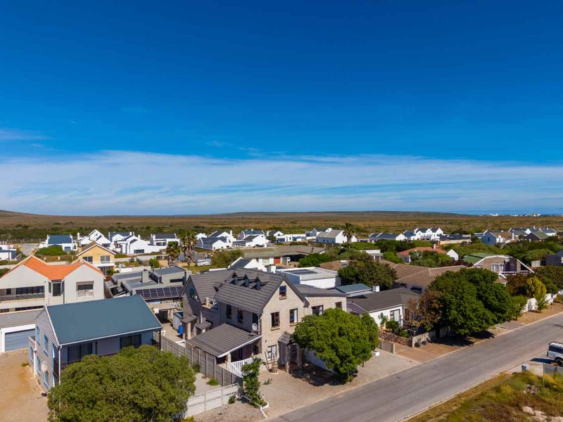 An aerial view of the property showing its position within the residential estate, featuring a tiled roof, solar panels, and surrounding neighborhood landscape.